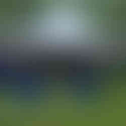 Round table with colorful table cloth and chairs underneath a white tent with string lights