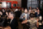 Guests laughing and raising glasses at dinner with a red food truck in the background at a wedding reception