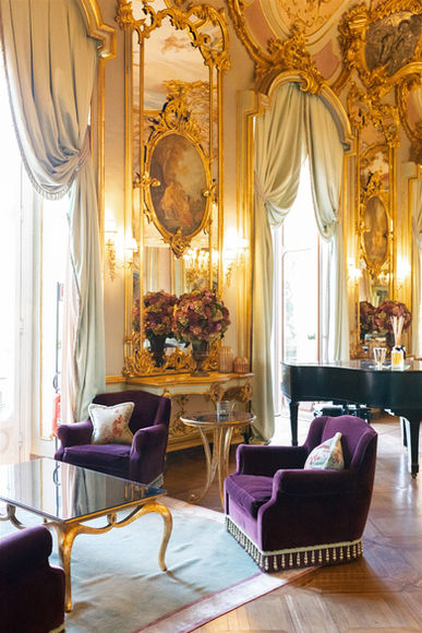 Elegant lounge with purple velvet chairs, gilded mirrors, and grand piano at Villa Cora in Italy.