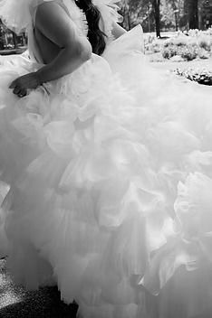 Bride in a dramatic ruffled tulle wedding gown walking outdoors on her wedding day.
