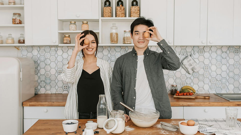 A cheerful couple preparing food in a stylish kitchen, holding eggs playfully.