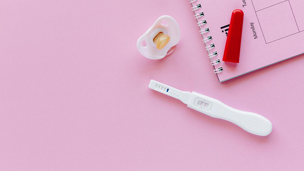 A positive pregnancy test on a pink surface with a pacifier and planner.
