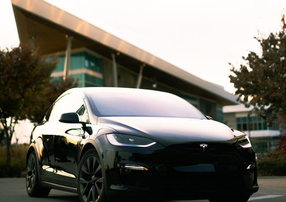 An impressively stylish, appealing black car turns a corner with a triangular building behind it at the Vancouver Waterfront.
