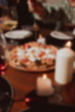 Toma de Pizza en la mesa junto a velas y comensales