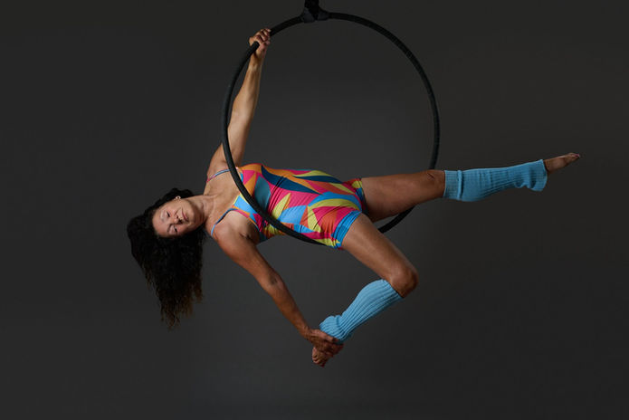 Woman in colorful leotard performing aerial hoop acrobatics gracefully