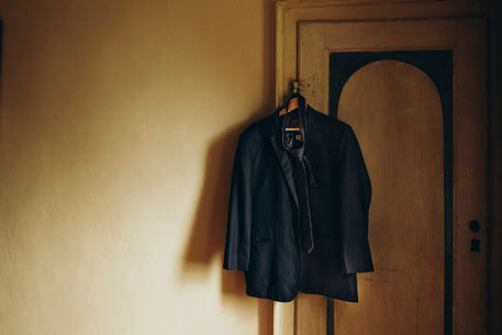 groom suit hanged on the wall in detail at wedding in Tuscany