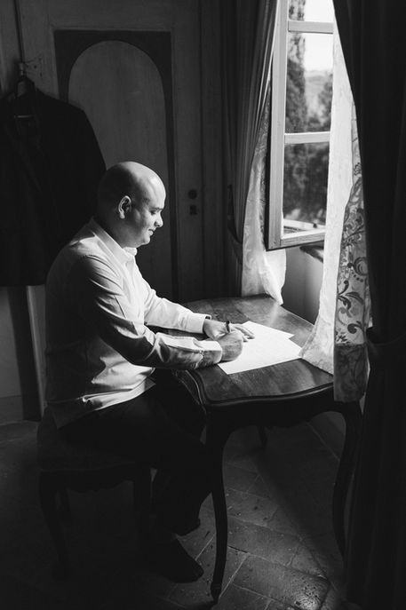 black and white portrait of groom writing vows for wedding in Tuscany