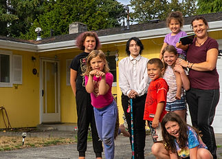 Large family standing in front of yellow house