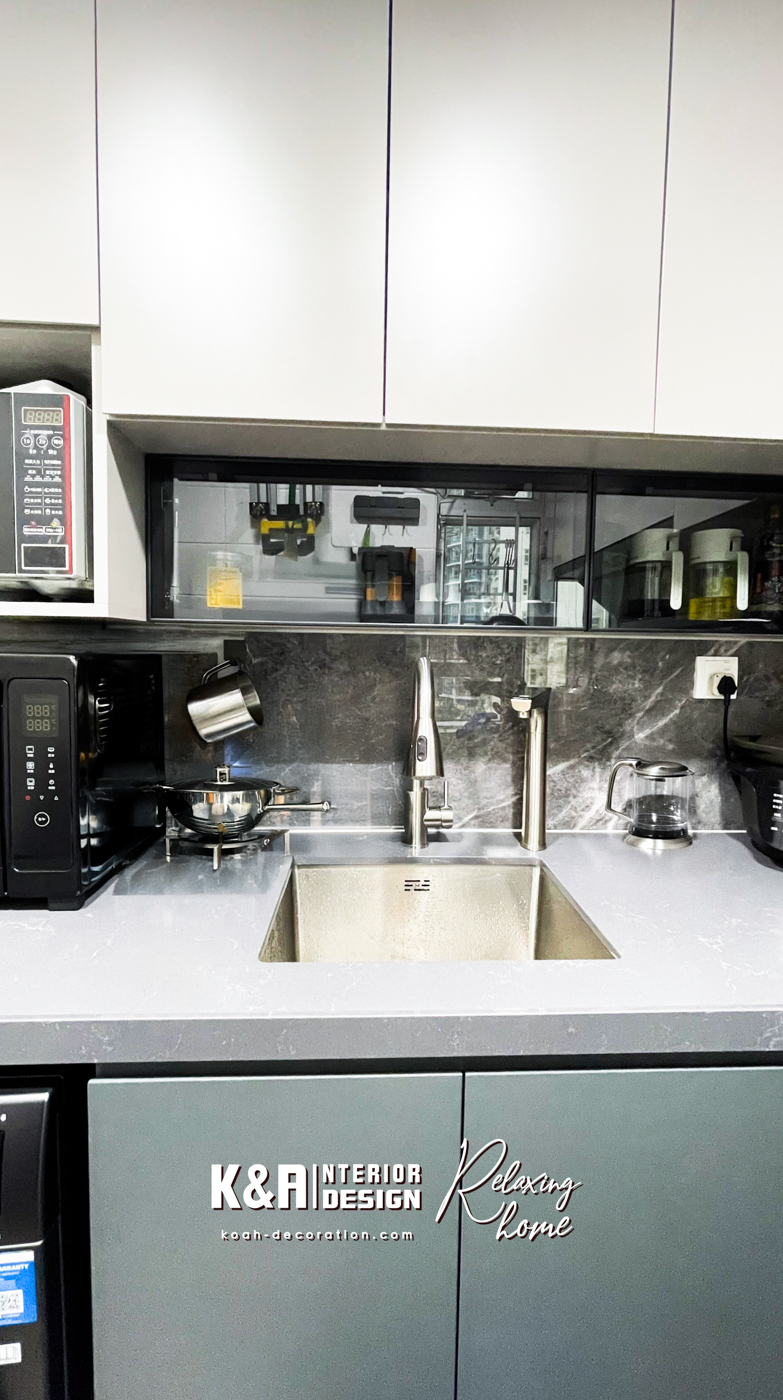 【廚房設計】經典L形廚房設計之下，以中灰調大理石紋理石材與暖白、深灰高質板材建構，盡顯高貴氣派，尺寸精準的訂造廚櫃組合，為戶主提供便利的入廚體驗，其中工作枱上強化玻璃吊櫃以「上翻門」設計，更便利於日常