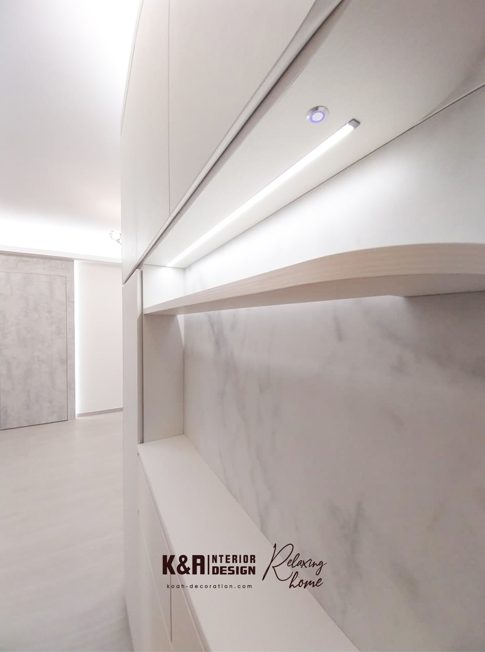 玄關延伸至客飯廳的收納系統：由玄關訂造收納櫃一直延伸至客飯廳的一體式圓角暖白收納櫃，為設計亮點。櫃體圓角設計柔和視覺，附輕觸按鈕LED燈帶的牆身窄櫃，提供出入門口置物功能（如鎖匙、車匙、房卡），底部還