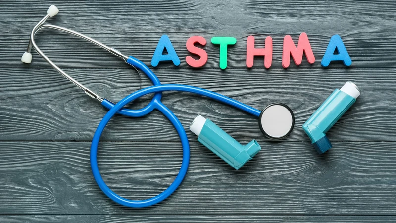 a stethoscope and asthma pumps on a table with the word asthma spelt out