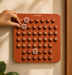 Hand turning the date knob on the Nithyam Pratham English Edition calendar in Clay