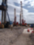 Construction site at Invergordon with large machinery including piling rig. Concrete platform in foreground with Cromarty Firth in background.