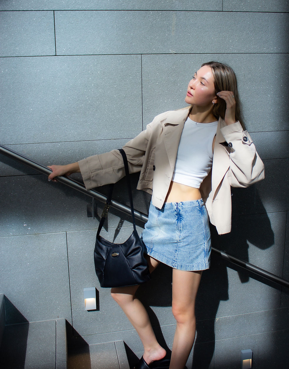 Thumbnail: Woman in white top and denim skirt ascends stairs, holding LALITA handbag.