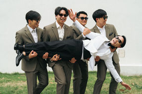 Groomsmen in suits carrying the groom horizontally – Thailand