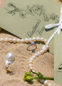 Sebaastiaan's Vows card with pearl necklace and diamond ring on sand – Ana Mandara, Cam Ranh