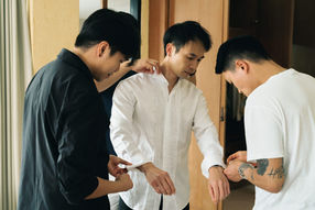 Friends helping the groom with his white dress shirt – Thailand