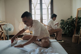 Groom smiling while ironing a white shirt for the wedding – Da Lat