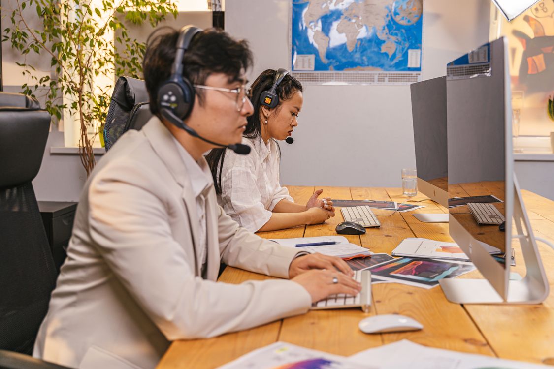 Stock photograph of call-center personnel working at computers with headsets