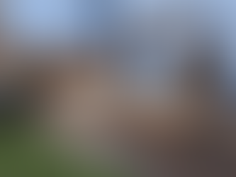 Wooden deck with black metal railings, steps, and a privacy fence in a backyard. Bushes to the left and an air conditioning unit right.