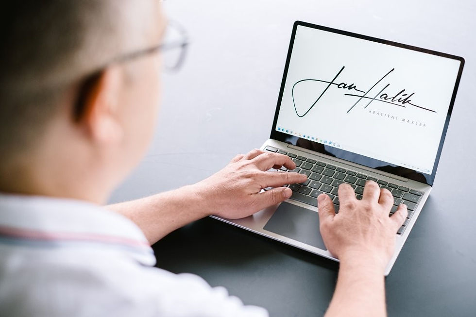 Muž pracuje na notebooku, na jehož obrazovce je logo realitního makléře Jan Halík.