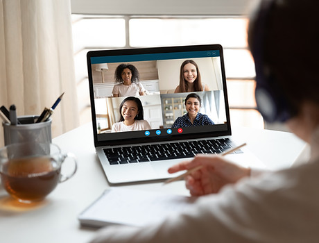 Woman sitting at desk noting writing information studying at home with multiracial student