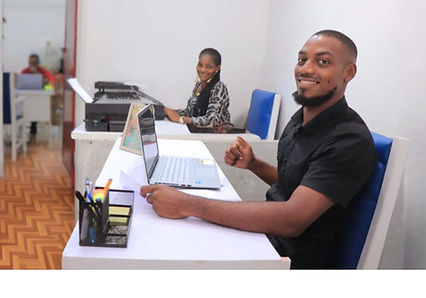une femme et un homme afro souriant dans un bureau avec des ordinateurs portable