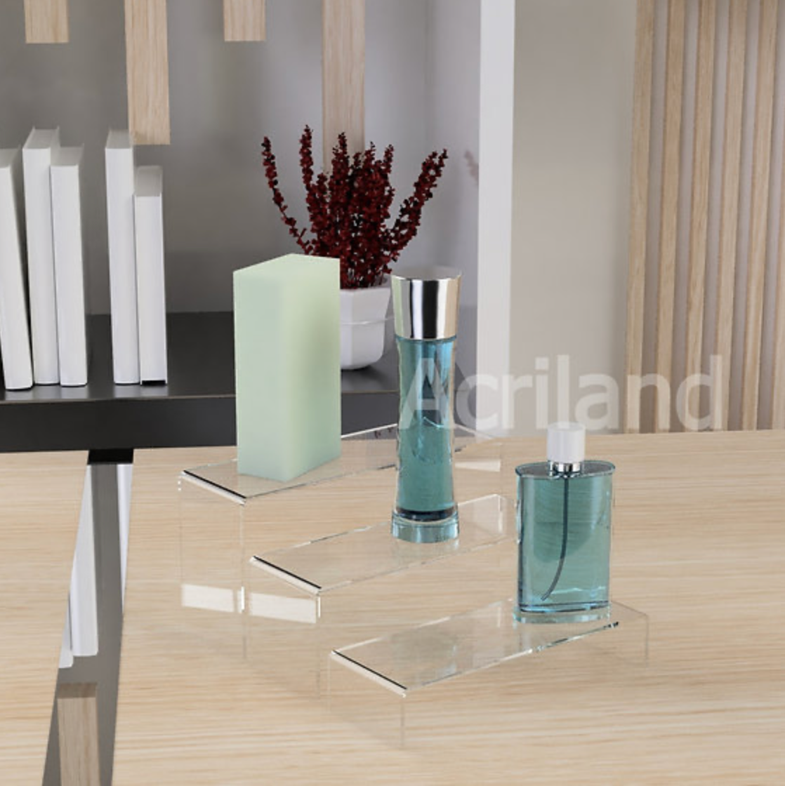 Exhibidor escalera tres niveles, de acrílico transparente.