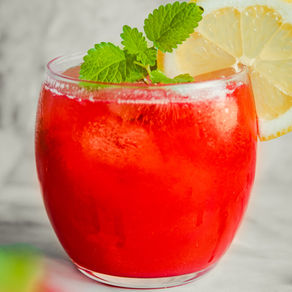 Rosa bringebærlemonade i glass med is, sitronskiver og sitronmelisse