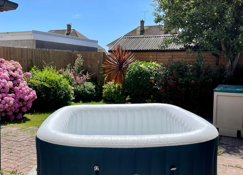 A blow up hot tub in the back garden with blue sky.