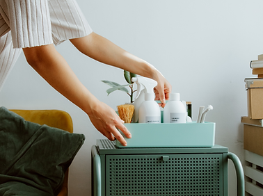 Hands placing a small home organization caddy with cleaning essentials on a cabinet, representing light home organization and daily living support.