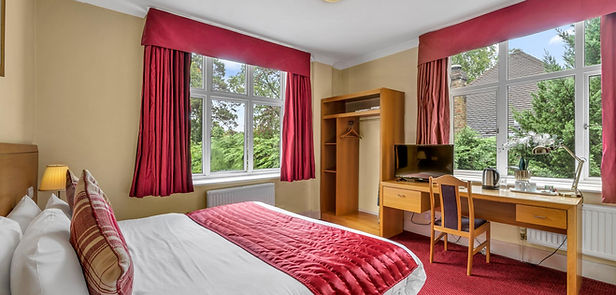 Bright hotel bedroom with red curtains and desk