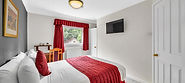 Modern hotel room with a red bed runner and curtains.