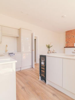 Modern kitchen with white cabinetry and brick accent wall