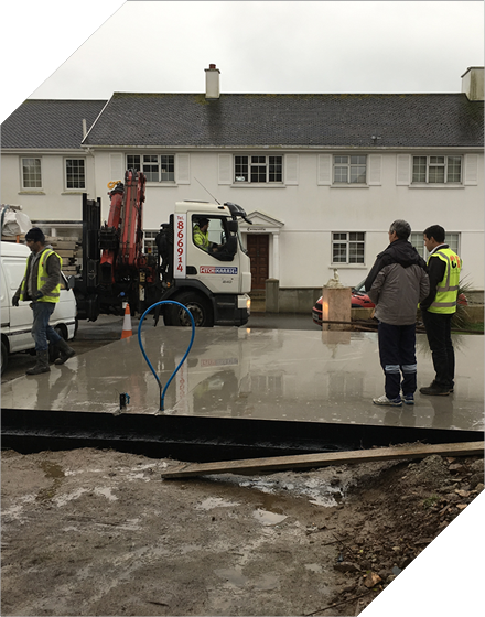 Construction workers near a truck with a crane in front of a building. Cf Construction
