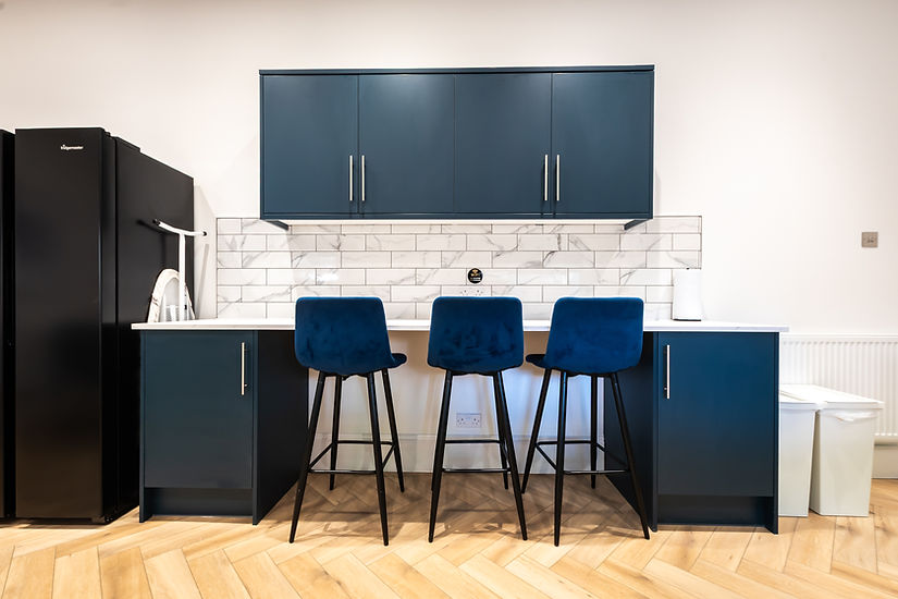 Modern WJO Stays kitchen area with blue stools and marble tiles.