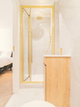 Modern ensuite bathroom with gold-framed shower and vanity.