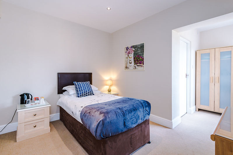 Cozy hotel bedroom with a single bed and essential amenities. CONTRACTOR STAYS