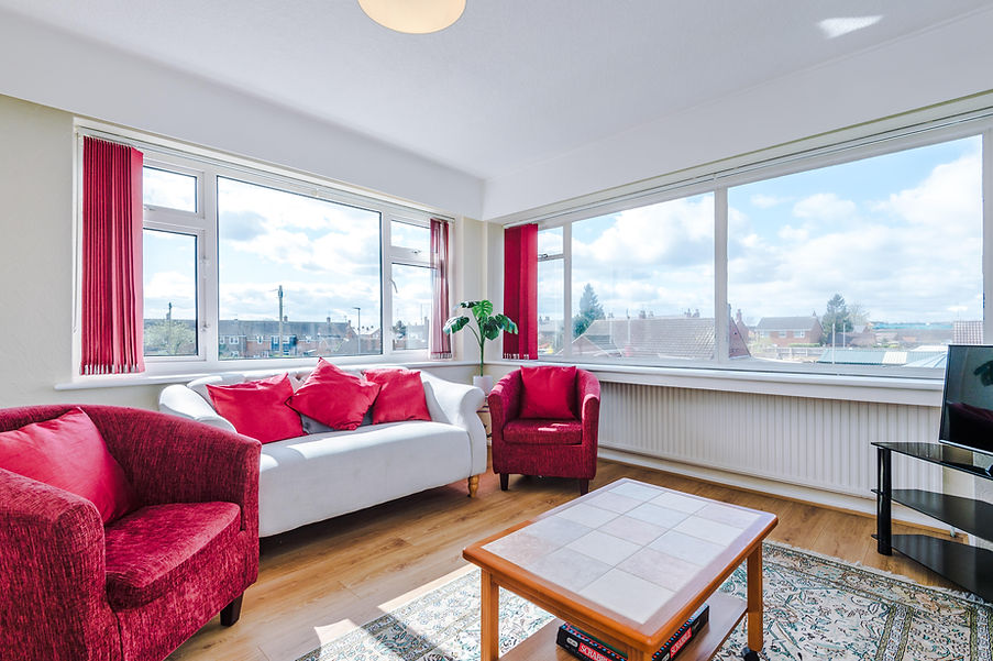 Cozy living room with red accents and large windows for natural light.