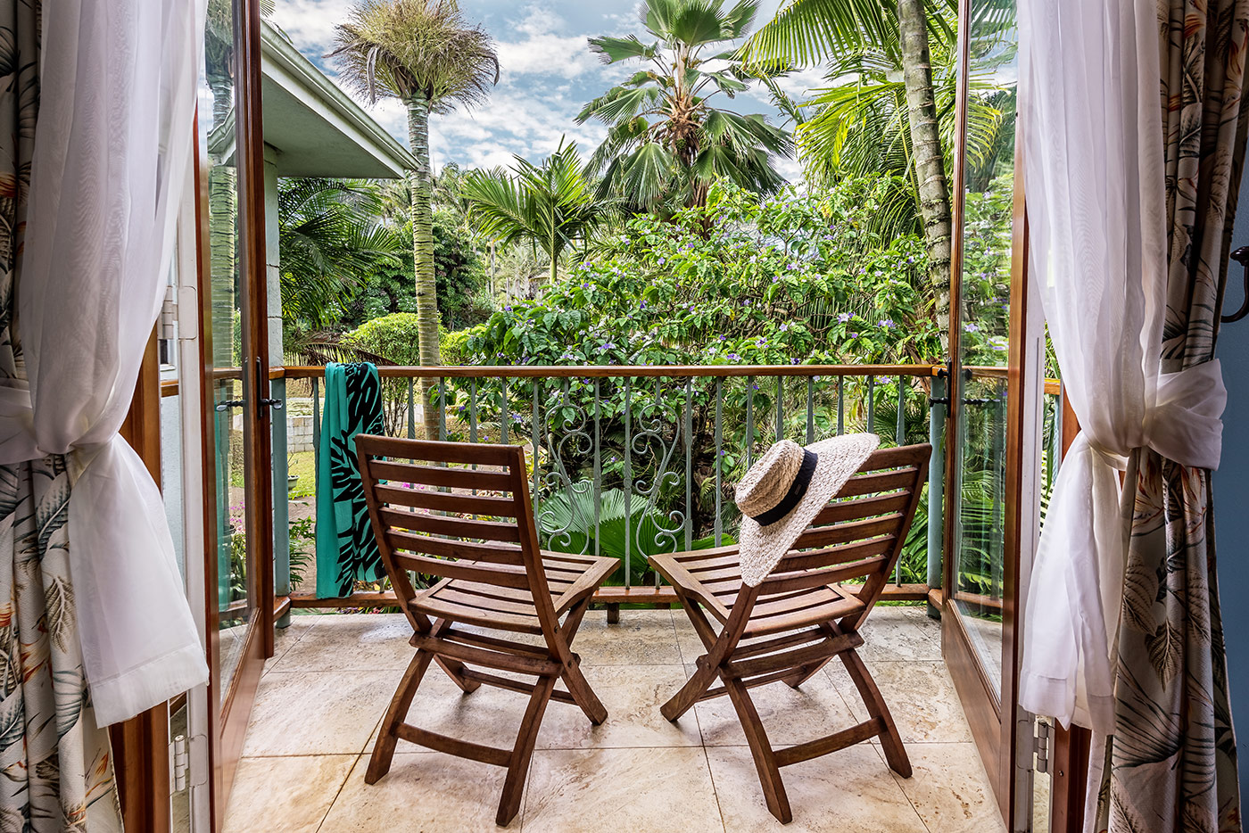 Wooden chairs on a balcony overlooking tropical palm trees
