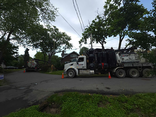 VacPro hydro excavation trucks performing utility work in a residential neighbourhood with traffic cones for safety.
