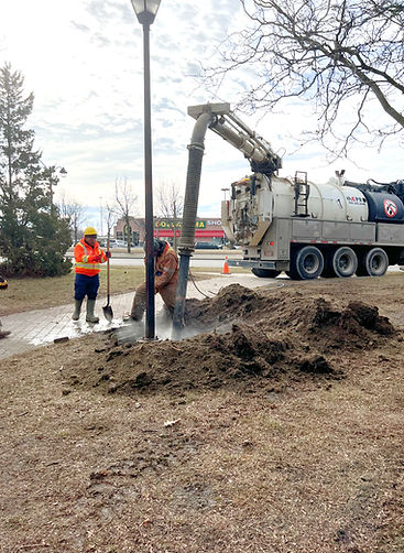 VacPro crew using a hydrovac truck to excavate around a light pole base.