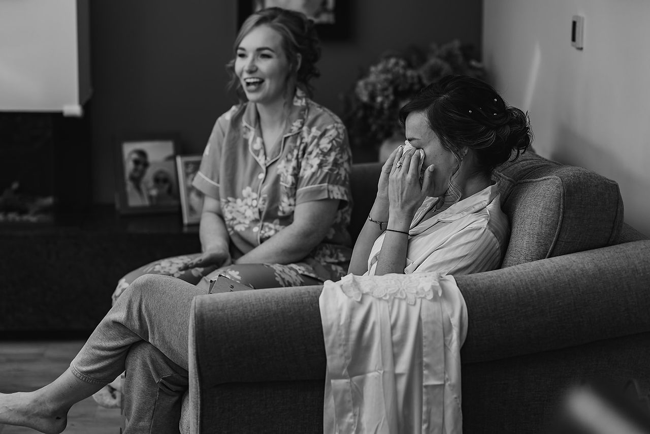 A bride cries happy tears with her bridesmaid while getting ready for her wedding at Mayfield Farm