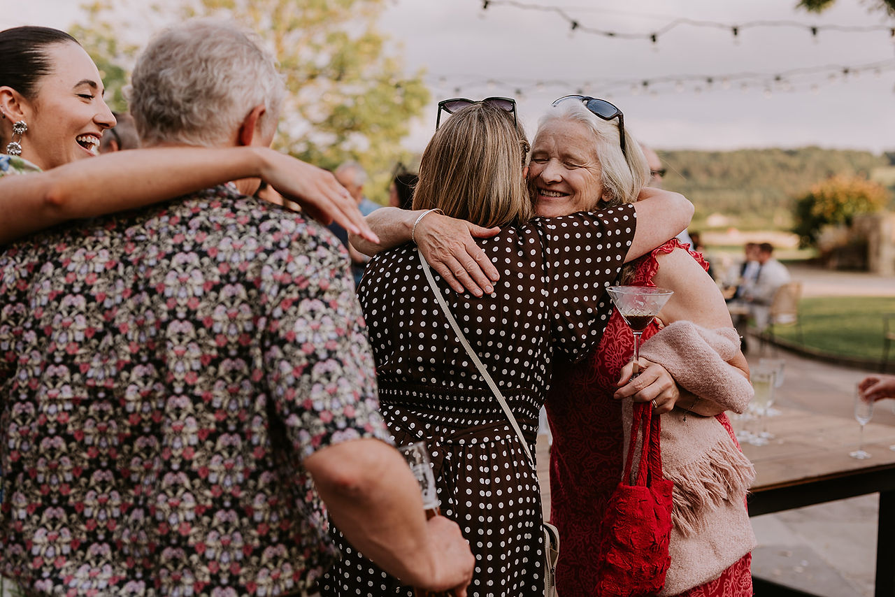 Wedding guests are all hugging and smiling in the sunshine at Wharfedale Grange.