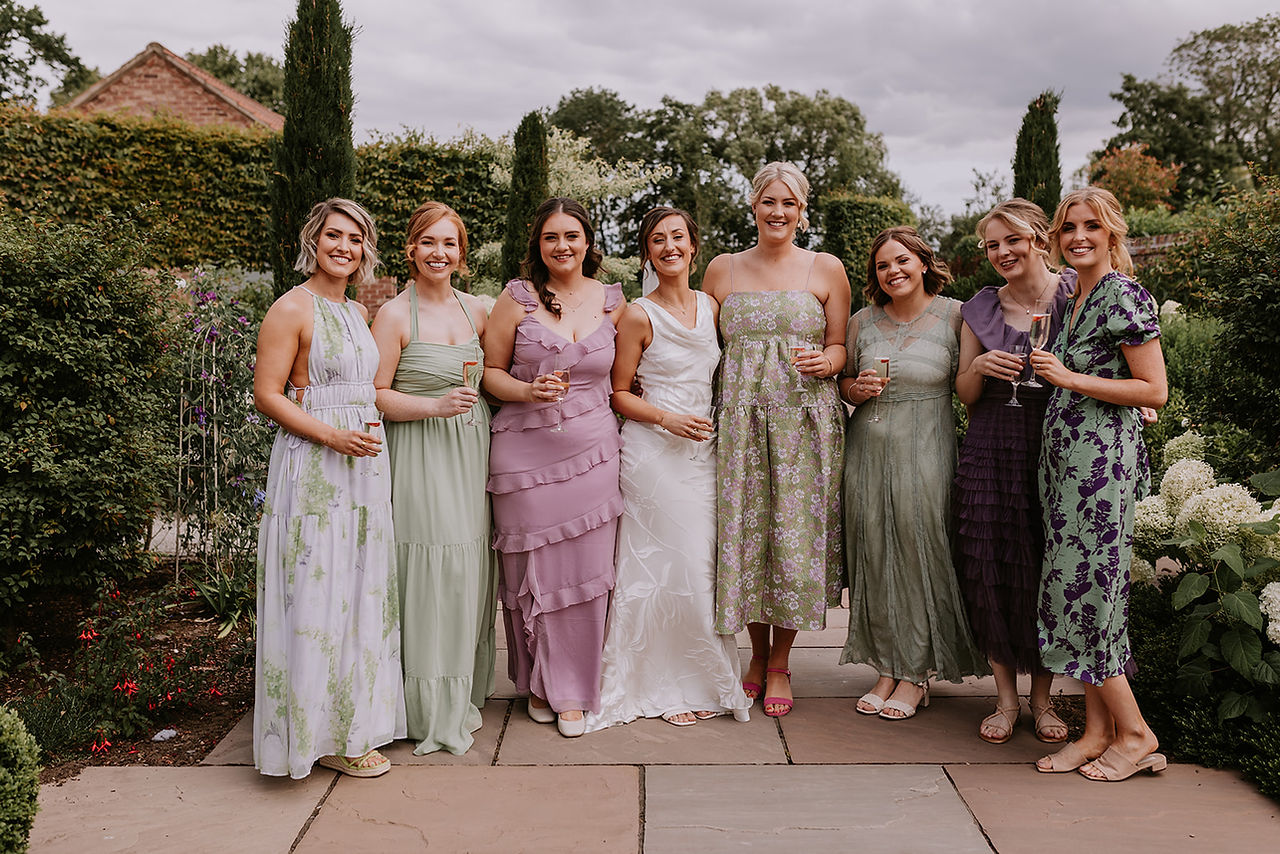 The bride and her bridesmaids in their mix and match summer bridesmaids dresses ready for the wedding at Mayfield Farm