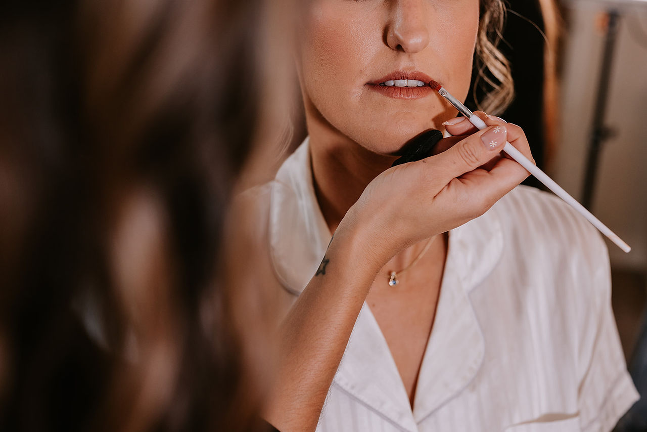 The bride is getting her lipstick perfected ready for her wedding at Mayfield Farm