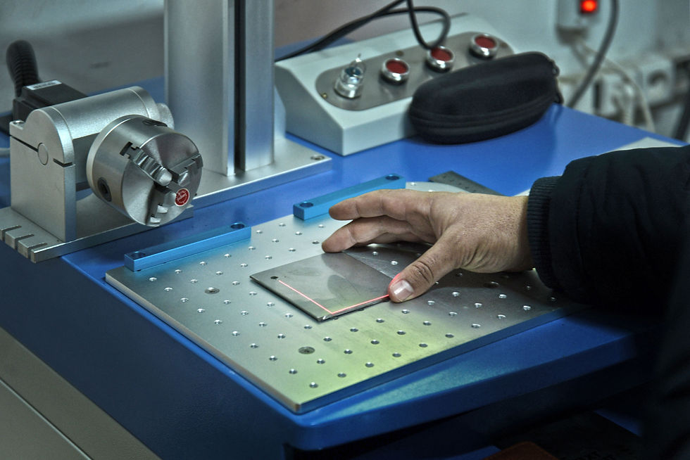 A hand placed on a laser engraving machine's surface with controls in the background.