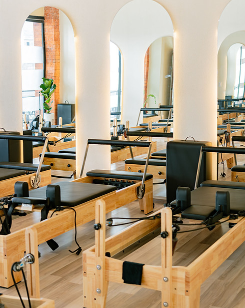 Bright modern Pilates studio interior with reformer machines neatly arranged in rows