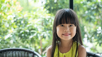 Young girl smiling and sitting in a chair.
