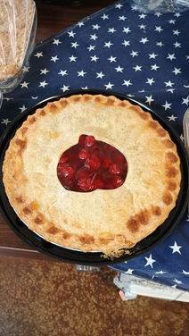 Cherry pie on a plate, surrounded by a blue star patterned cloth.